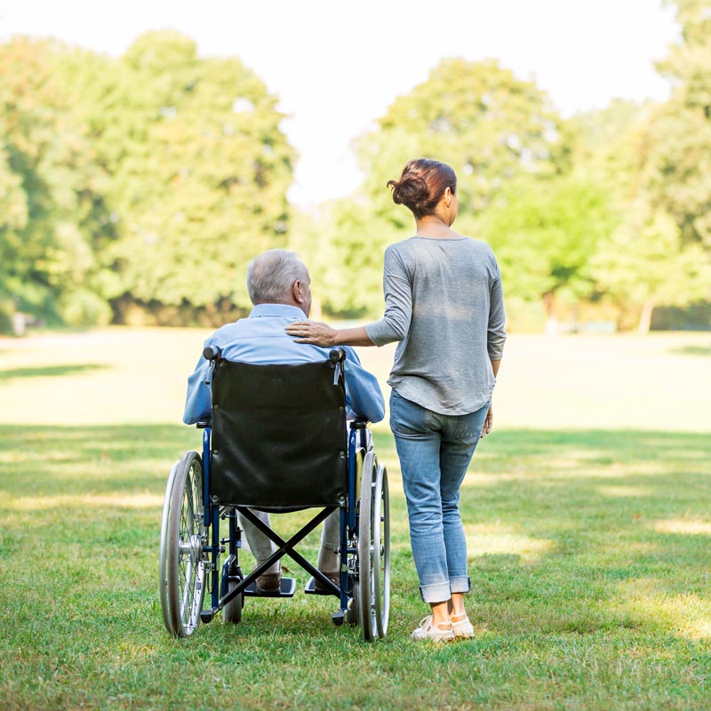 caregiver with man in wheelchair in park