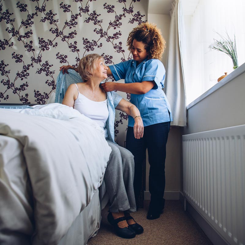 caregiver helping senior woman dress
